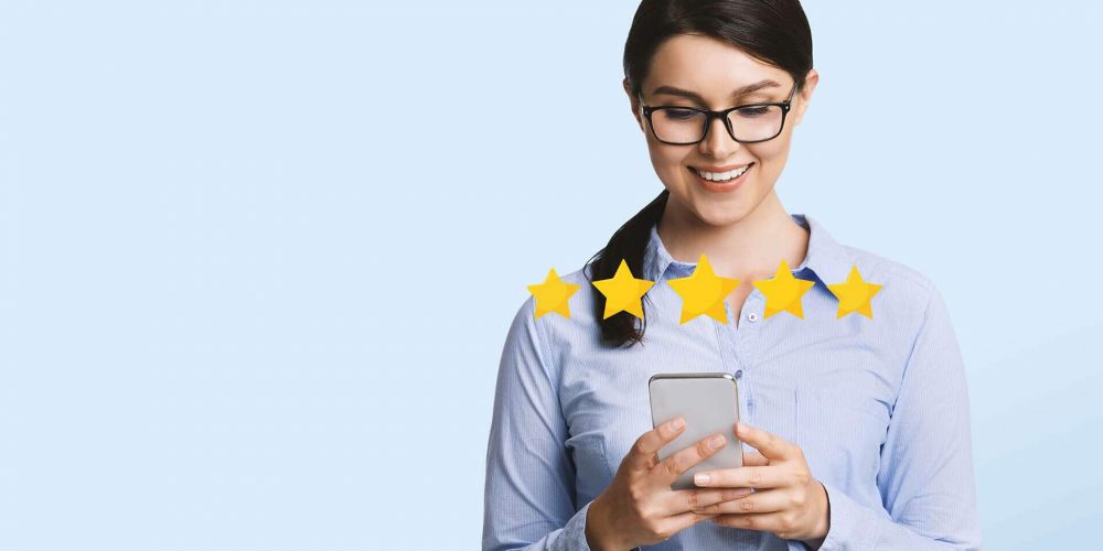 Woman smiling at smartphone leaving 5 star review